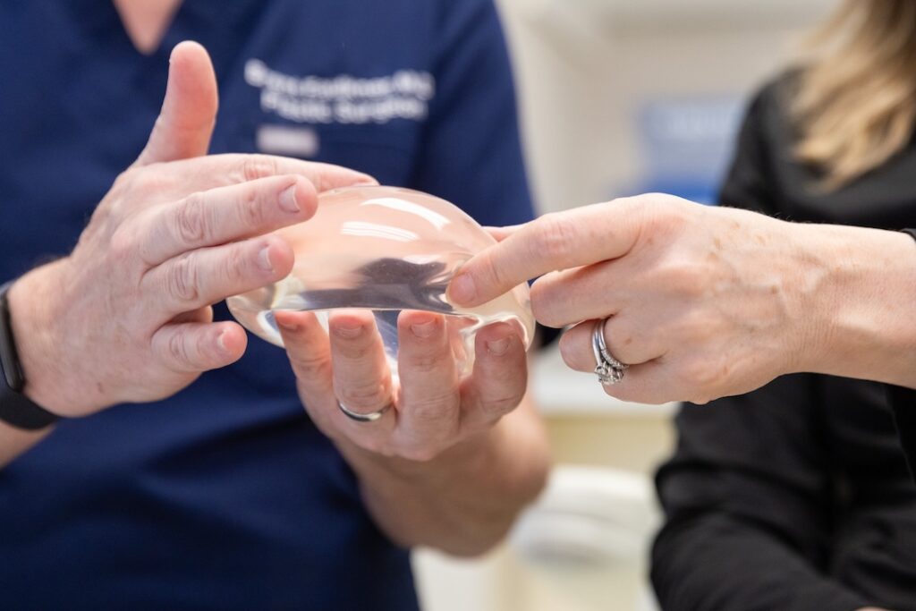 A close up of a physcian's hands showing a client a breast implant before their breast aug near Bethesda, MD.